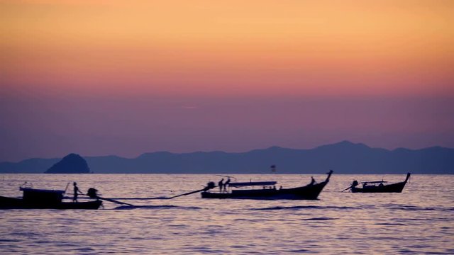 Long-tail boats silhouettes in the sea at sunset 