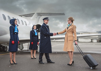 Full length outgoing lady greeting with glad pilot. Optimistic air-hostesses standing near...
