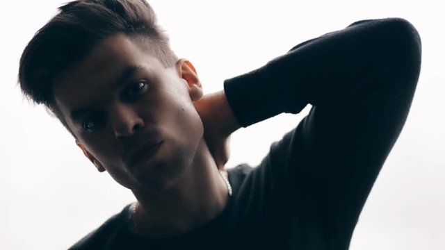 Portrait of a young guy on a white background, with a thrown arm behind his head