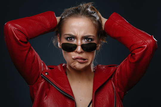 Portrait of a young woman in a red leather jacket and sunglasses