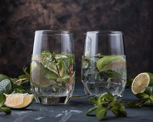 Glasses of Mojito with lime and mint. Summer refreshing cocktail on a grey metal background