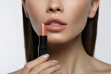 Close up of passionate girl holding pink lipstick near her mouth. Isolated