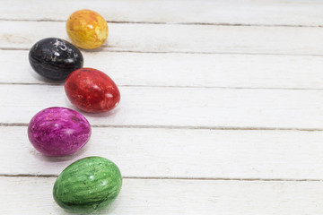 Easter greeting card with colored green, yellow, violet and red eggs over old wooden background.