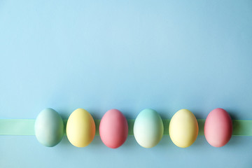 Different pastel color Easter eggs laid and arranged in beautiful composition with white wildflowers. Greeting card with copy text space.