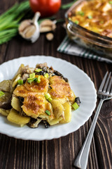 Potato casserole with meat and mushrooms on a wooden background