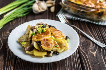 Potato casserole with meat and mushrooms on a wooden background