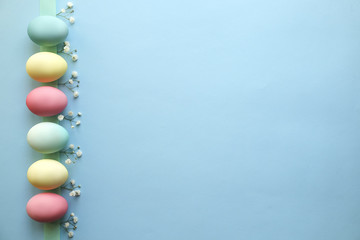 Different pastel color Easter eggs laid and arranged in beautiful composition with white wildflowers. Greeting card with copy text space.