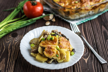 Potato casserole with meat and mushrooms on a wooden background
