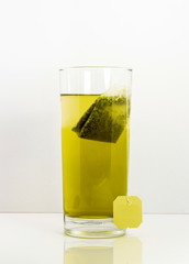 green tea glas with bag isolated with white background and reflection
