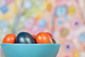Fototapeta na wymiar Easter eggs in a blue bowl on colourful background