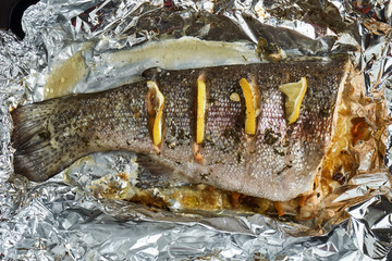 Trout with slices of lemon prepared in an aluminum foil