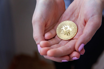 Fototapeta premium Cryptocurrency golden bitcoin coin in woman hand. Electronic virtual money for web banking and international network payment. Symbol of crypto currency
