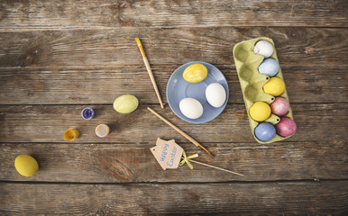 Easter concept. Top view of colored eggs, paint and brushes on wooden table