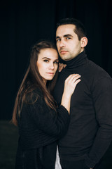 Portrait of a beautiful couple who stands on a black background and looks at the camera