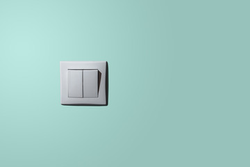 White light switch on a pastel background. The concept of electrical wholesalers, stores with electronic accessories. Minimalism. On the blue, turquoise pastel background there is a light switch.