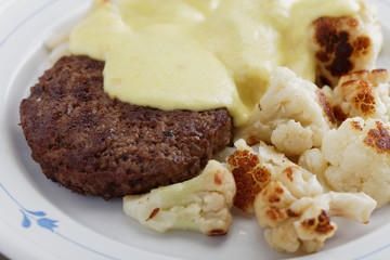 Meat burger with cauliflowers under cheese sauce