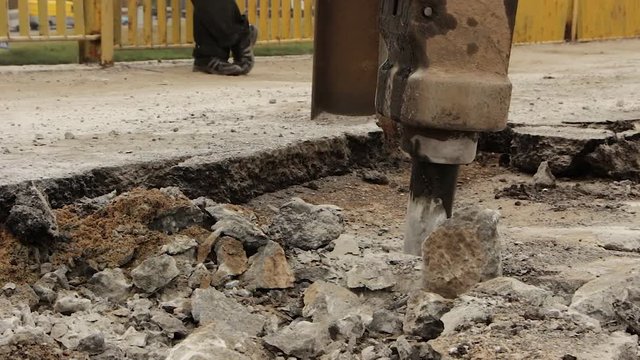 Close up of hydraulic arm hammer breaks the asphalt on the road