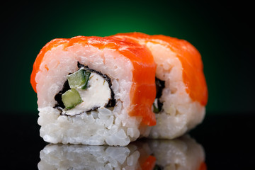 Rolls with red fish and cucumber on a black background. Japanese restaurant menu, close-up