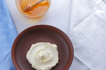 Fresh cottage cheese with honey on a white background, soft cheese with a blue napkin, dairy product with honey, healthy food, French breakfast, American cuisine, minimalism, curd with goat milk