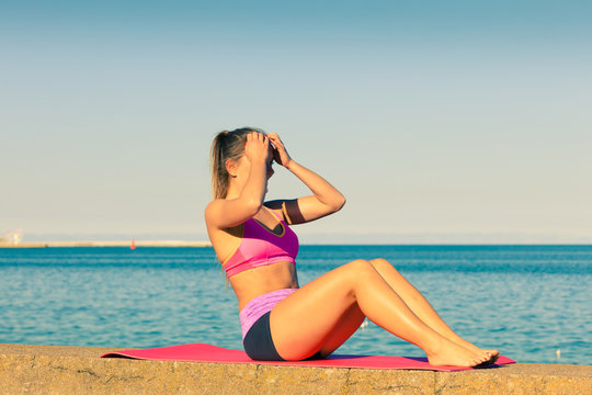 Woman doing sports exercises outdoors by seaside