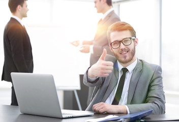 Fototapeta premium Manager sitting at his Desk and showing thumbs up