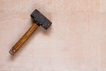Hammer worn diagonally, in the left corner, on a wooden table