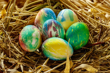 Fototapeta na wymiar Many multi-colored Easter eggs lie in the nest. Nest of grass and branches.