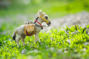 A donkey in a clearing of green grass. A loaded donkey on a green background.