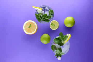 Mojito on an ultraviolet background, a cocktail with mint, lemon and lime, a soft drink for summer relaxation, a cocktail on a purple background, a pop art drink, half a lemon and lime, minimalism