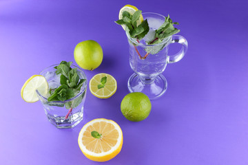 Mojito on an ultraviolet background, a cocktail with mint, lemon and lime, a soft drink for summer relaxation, a cocktail on a purple background, a pop art drink, half a lemon and lime, minimalism