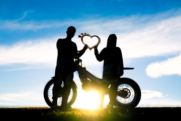 Obraz na płótnie Canvas silhouette of romantic lovers and motocross with sunset