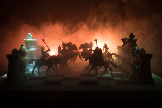 Medieval battle scene with cavalry and infantry on chessboard. Chess board game concept of business ideas and competition and strategy ideas Chess figures on a dark background. Selective focus