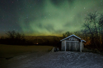 Beautiful aurora borealis over little cottage in Abisko, Lapland, Sweden, northern lights at night