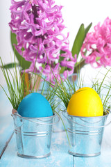 Easter eggs on a blue wooden table.Three colorfull egg in metal bucket.Flower hyacinth in bucket.Copy space.Eater background.Pastel colour