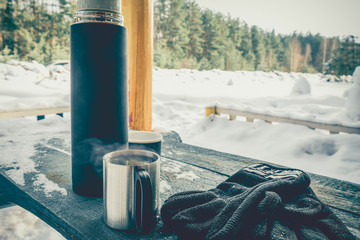 mug and thermos on the table in winter