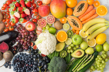 Healthy eating background, assortment of different fruits and vegetables in rainbow colours on the off white table arranged in a rectangle, top view, selective focus