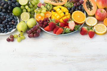 Fresh fruits and vegetables in rainbow colours on the off white table, copy space, selective focus