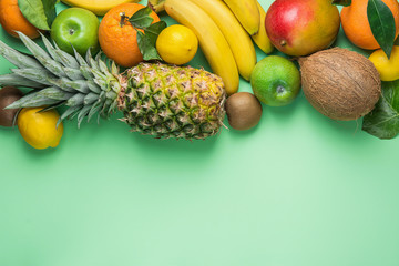 Variety of Different Tropical and Summer Fruits. Pineapple Mango Coconut Citrus Oranges Lemons Apples Kiwi Bananas Arranged in Border on Turquoise Background.Healthy Diet Vegan Vitamins. Flat Lay