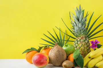 Composition from Variety of Different Tropical and Summer Fruits. Pineapple Mango Coconut Citrus Oranges Lemons Apples Kiwi Bananas Arranged on Stone Tabletop Yellow Background.Healthy Diet Vegan