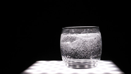Glass with soda water (bubbles), black background.	