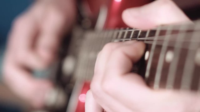 Electrig guitarist performing a solo, focus on fretting hand, cinematic
