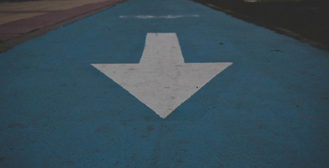 Arrow. White arrow on the blue floor. Road sign.