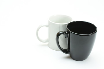 black coffee mug in front of white coffee mug, high key