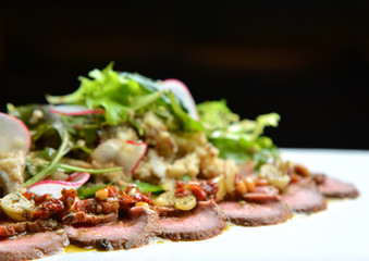 Sliced grilled beef steak with green leaves salad on rustic plate with radish. Medium rare barbecue steak
