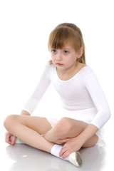 Girl gymnast sits on the floor and cries