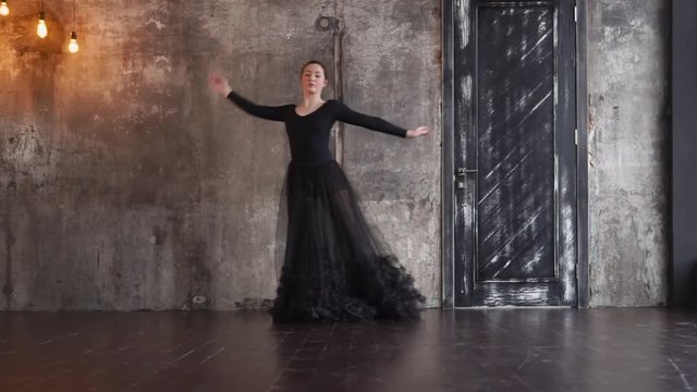 Lovely Woman Slowly Dancing In Her Black Dress Alone Against Concrete Wall And Old Door. Showing Passion And Love.