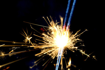 Sparklers as background /A sparkler is a type of hand-held firework that burns slowly while emitting colored flames, sparks, and other effects. 