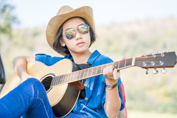 Close up woman wear hat and playing guitar