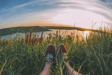 sunset  on the sea with grass and mountains and shoes