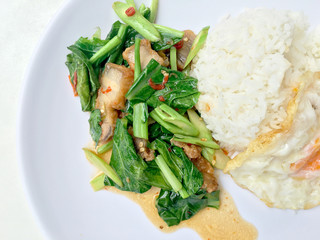 Stir fry Kai Land and crispy pork, stir fried rice with rice in white dish on white background. Thai style food.